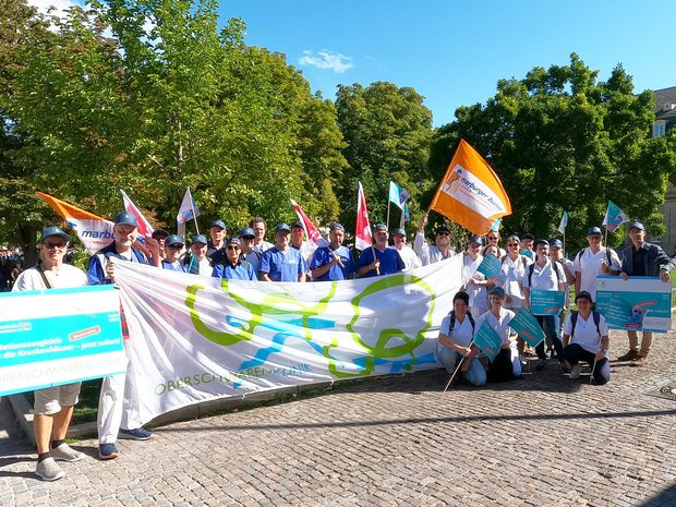 Sie halten die Fahne für die OSK hoch: 29 Mitarbeiter aus Ravensburg und Wangen haben am Mittwoch am bundesweiten Protesttag der Kliniken in Stuttgart für mehr finanzielle Unterstützung für Krankenhäuser protestiert.